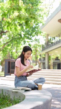 Relaxed young student woman reading a book in university campus.