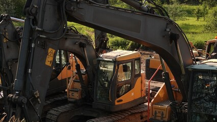 Bliskie ujęcie poziome przedstawiające kabinę operatora oraz potężną konstrukcję ramienia hydraulicznego ciężkiej koparki gąsienicowej. © tomo81