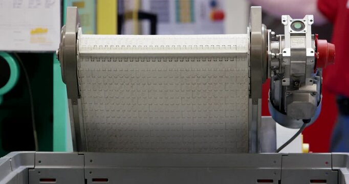 A view of white plastic components moving along an industrial conveyor belt system in a manufacturing plant