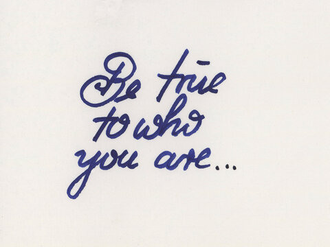 Cursive handwriting in blue ink on white paper spells "Be true to who you are..." The script has an elegant, flowing style.