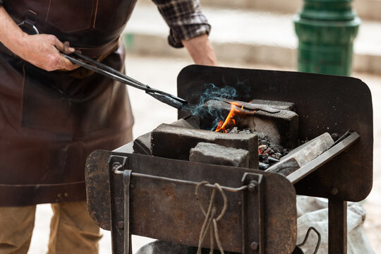 Blacksmith Heating Metal in Outdoor Coal Forge