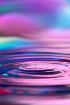 Water drop on pink iridescent surface with ripple