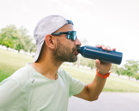 Man Drinks Water From a Bottle During Outdoor Activity in Park