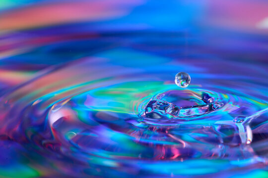 Water drop splash on iridescent rainbow surface macro
