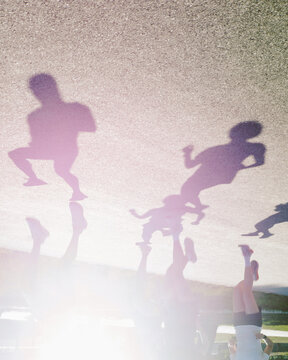 People Running on the Street With Shadows Showing on the Ground