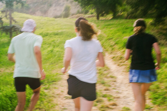 People Running on a Trail in a Green Landscape During the Day