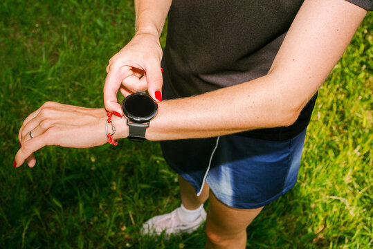 A woman checks her running stats on her smartwatch after a workout