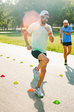 Men Train for Fitness on a Running Track in Sunny Weather