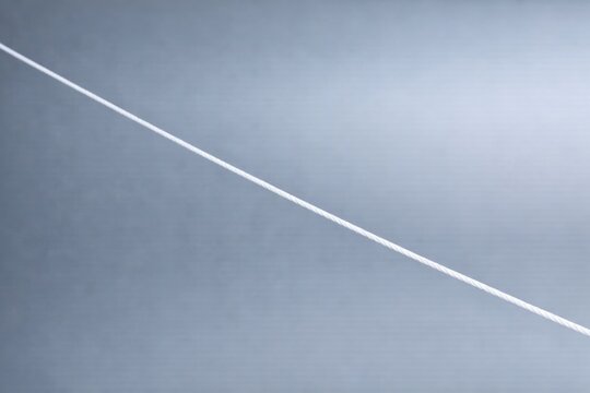 A plane flying through the clear blue sky with a contrail visible behind it