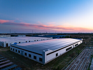 Fototapeta premium Industrial park rooftop photovoltaic energy storage station at dusk with sunset and clear sky