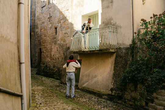 two young women climbing on balcony  in village in the South of France