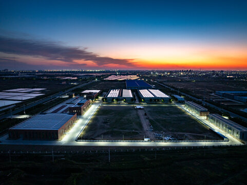 Aerial view of industrial park at dusk with illuminated buildings and solar panels