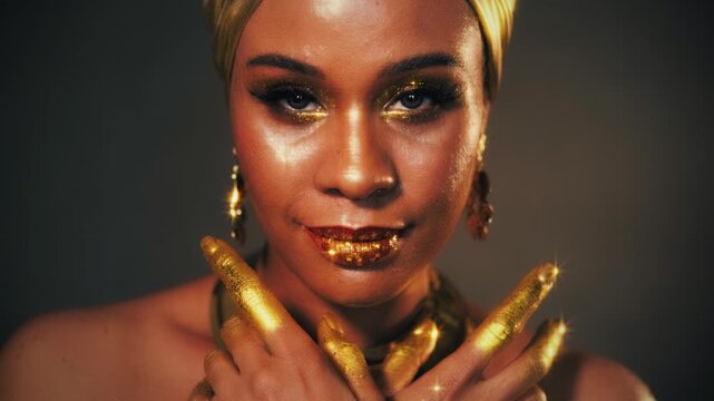 Portrait Beauty fantasy african happy woman smiling faceeye shadow gold paint. Golden makeup liquid gold shiny skin. Fashion model girl. arab turban on head earrings necklace set gold metal jewelry 4k