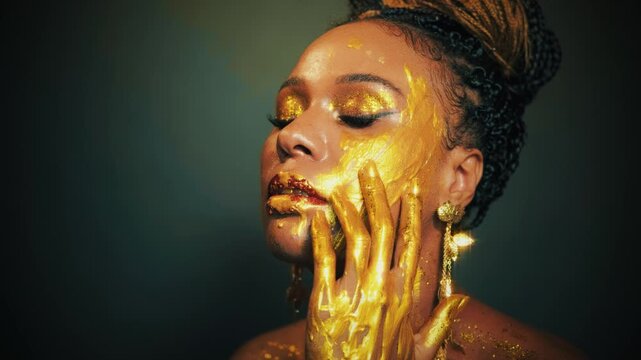 fantasy art portrait lips eyes close up face african american woman. Professional creative golden make-up shiny shadows. Hands in gold liquid drops flow sexy Fashion model beautyl girl. Studio black