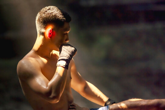 Professional male boxer ready to fight in low-key lighting boxing gym