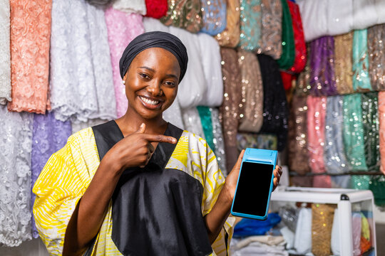 African woman entrepreneur holding pos machine, promoting small business sales