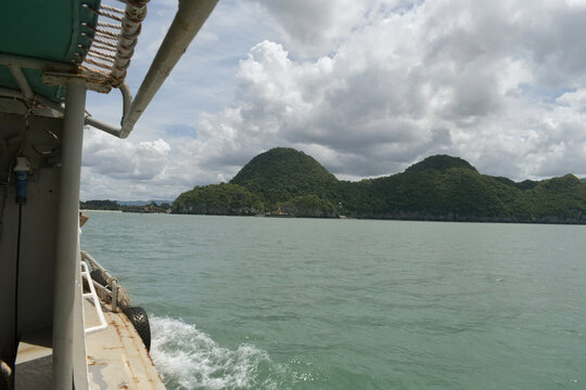 scenic view of the khanom coastline in southern thailand captured from a moving boat, featuring lush limestone hills, calm sea, and dramatic tropical clouds