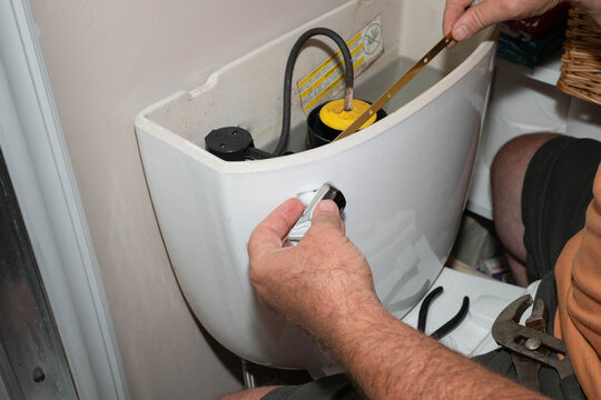 Placing a new handle fixture on a toilet tank in a residential house.