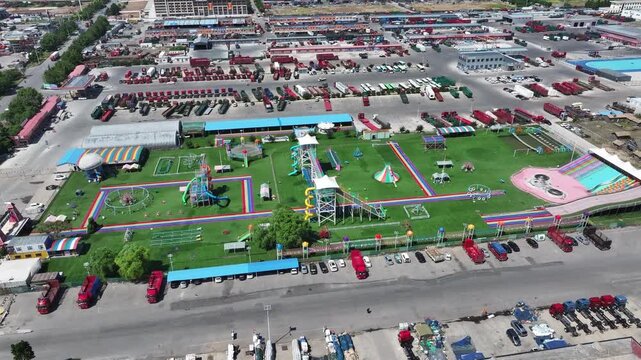 Aerial view of a large childrens playground with colorful equipment and adjacent vehicle parking area in Rizhao