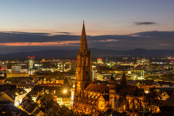 Obraz premium Evening view of Freiburg with illuminated cathedral and city lights