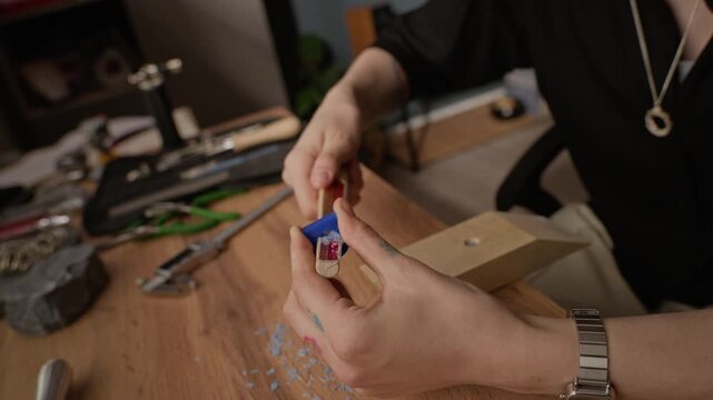 Close up of young adult Caucasian jeweler shaping blue wax ring model on wooden mandrel in workshop. Footage perfect for promoting handmade jewelry brands and small business marketing