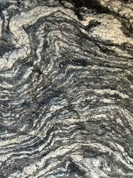 Close-up of folded metamorphic rock texture with black and white wavy layers