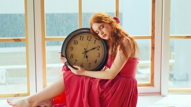 Fantasy portrait woman princess sits at window, eyes closed. Girl sleeping holding in hands beauty large round black digital watch alarm clock. Vintage dress. Redhaired fairy dream lady, long red hair