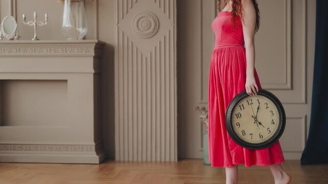 Romantic fantasy woman go to window. No face. Mysterious girl holds round antique clock in hand. Black numerals, white dial. Red elegant vintage retro midi dress. Backdrop modern victorian style room