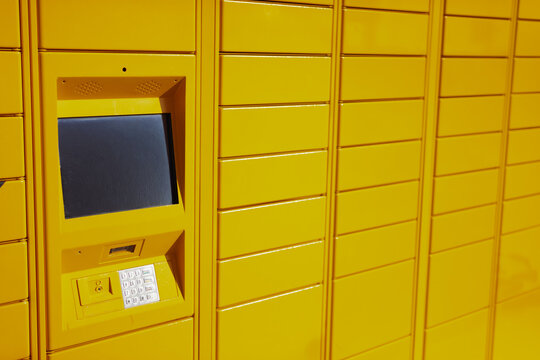 Yellow automated parcel locker with touch screen panel and keypad for convenient self-service package delivery and collection at a modern logistics terminal