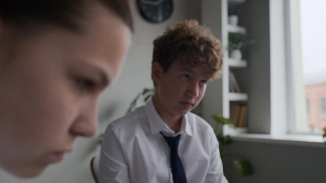 Sad teen girl sitting near her classmate while they listening to therapist. Perfect for educational marketing and school promotional videos