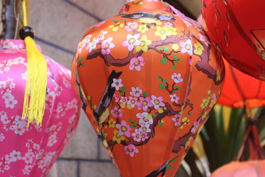 Vibrant orange lantern adorned with cherry blossom branches and colorful birds.
