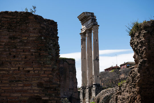 Framed view of the ancient columns of the Temple of Castor and Pollux through historic stone ruins at Forum Romanum in Rome, Italy