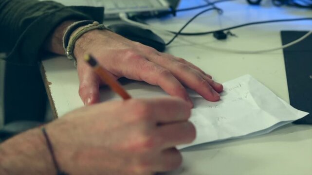 mani di giovane uomo adulto mentre scrive su carta e lavora ad un progetto 