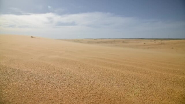 Close-up Sand dunes shift under gentle wind, creating ripples in the desert landscape