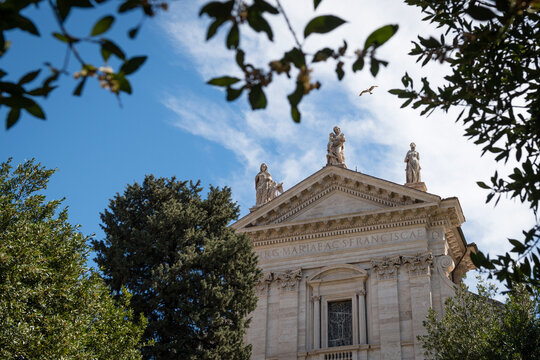 Framed view of the baroque facade of Santa Francesca Romana church with statues against blue sky in Rome, Italy