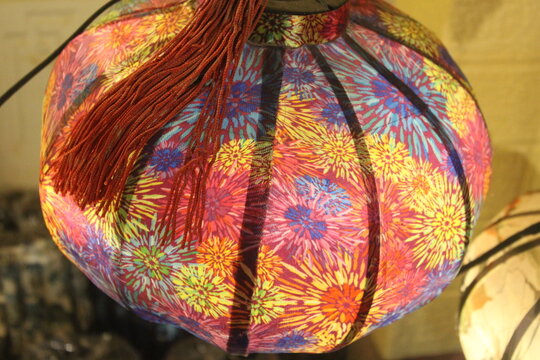 Colorful round lantern with firework design fabric hanging in traditional market.