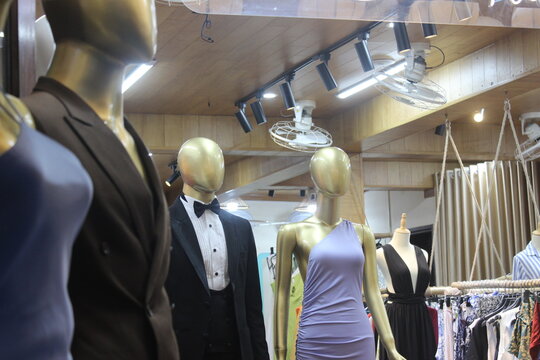 Gold mannequins dressed in formal evening wear on display inside boutique outlet.