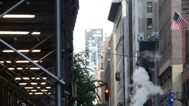 New York City Downtown or Midtown urban buildings architecture, Manhattan street, United States of America. Hot steam smoke vapor. Sidewalk pavement scaffolding, construction maintenance. USA flag.