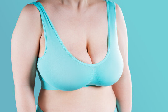Curvy woman with large saggy breasts wearing comfortable blue sports bra. Body positivity, lingerie or breast health concept