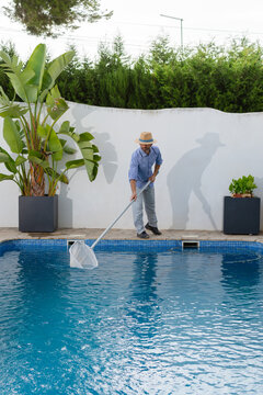 Vertical shot of pool cleaner removing leaves and flowers with skimmer net
