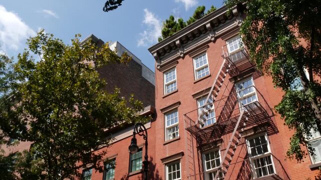 New York City urban residential buildings architecture, Manhattan classic street, United States of America. Typical red brick house in NYC, real estate property in USA. Fire escape metallic ladder.