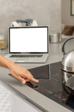 Close up of hand turning on modern induction cooktop in home kitchen