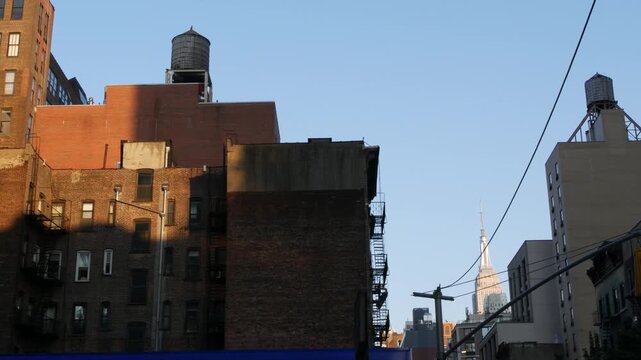 New York City Midtown urban red brick building architecture, Manhattan rooftop, United States of America. Water tower on roof. Classic water tanks. Hells Kitchen, Chelsea, Port Authority area. Sunset.