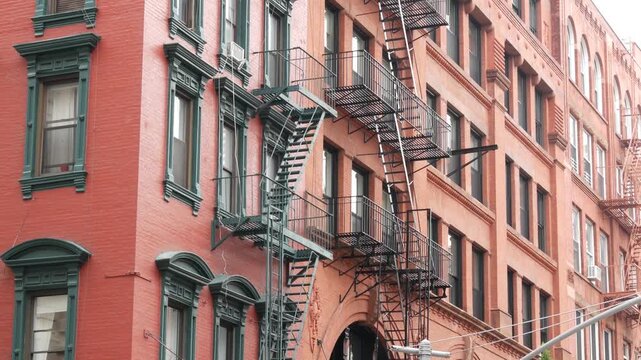 New York City urban residential buildings architecture, Manhattan classic street, United States of America. Typical red brick house in NYC, real estate property in USA. Fire escape metallic ladder.