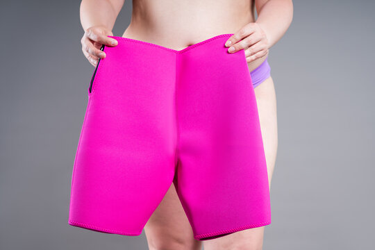 Overweight woman holding pink neoprene slimming shorts. Weight loss, and body shaping concept