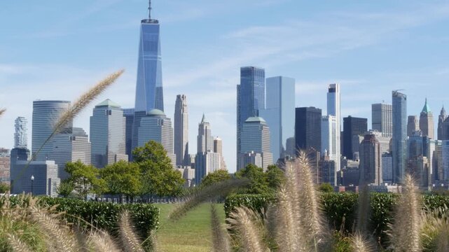 New York City Manhattan Downtown Financial District skyline, World Trade Center tower from New Jersey Liberty state park, United States. Green grass lawn, flowers and skyscraper buildings cityscape.