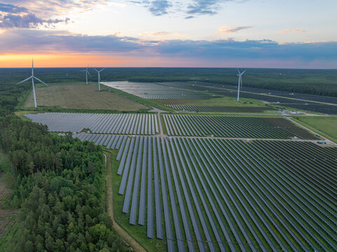 Aerial view of a large solar farm with wind turbines at sunrise near Pope, Ventspils Municipality, Latvia