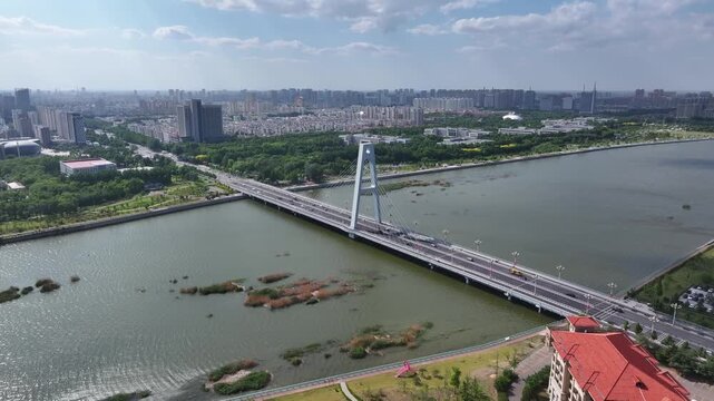 Aerial view of a cable-stayed bridge spanning a river in Rizhao city with urban skyline and green spaces