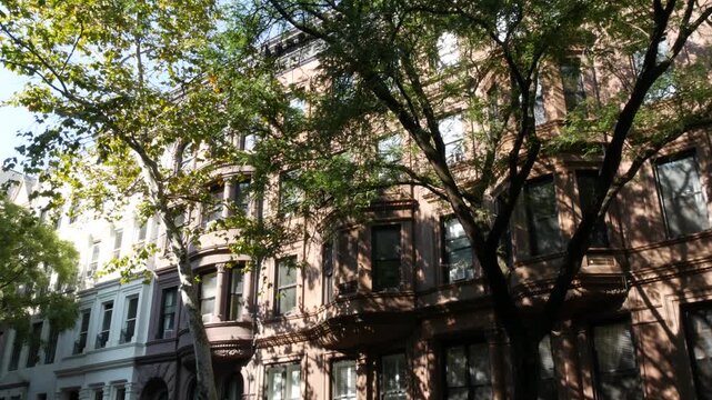 New York City townhouse buildings, brownstone row houses in Manhattan or Brooklyn, United States of America. Classic buildings on residential district street. Real estate property. Rowhouse townhome.