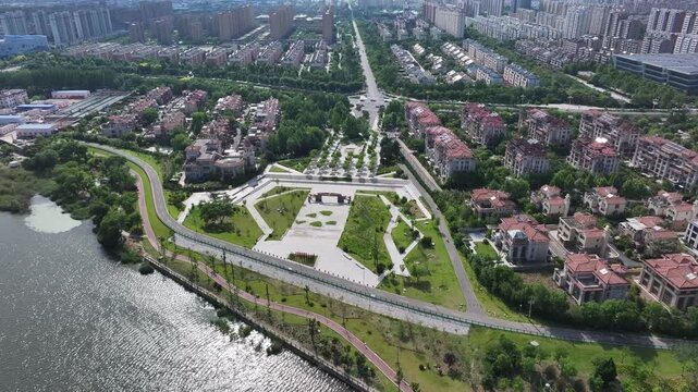 Aerial view of a riverside park adjacent to residential neighborhoods with green spaces and modern architecture